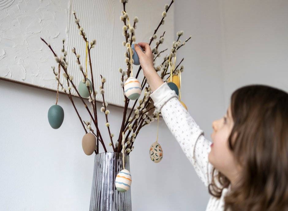 Des branches dans un vase, décorées avec des œufs de Pâques 